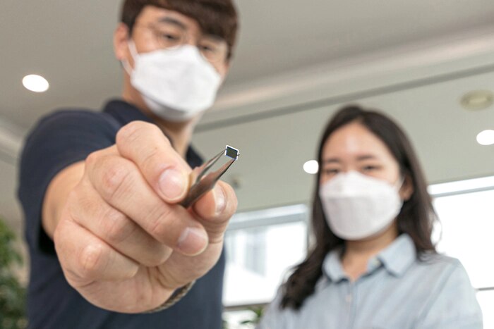 A man is holding a ISOCELL JN1 chip with tweezers.