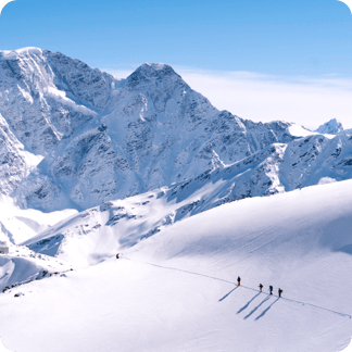 晴朗的天空下，在白雪皑皑的山脉上徒步旅行的人们的样子。