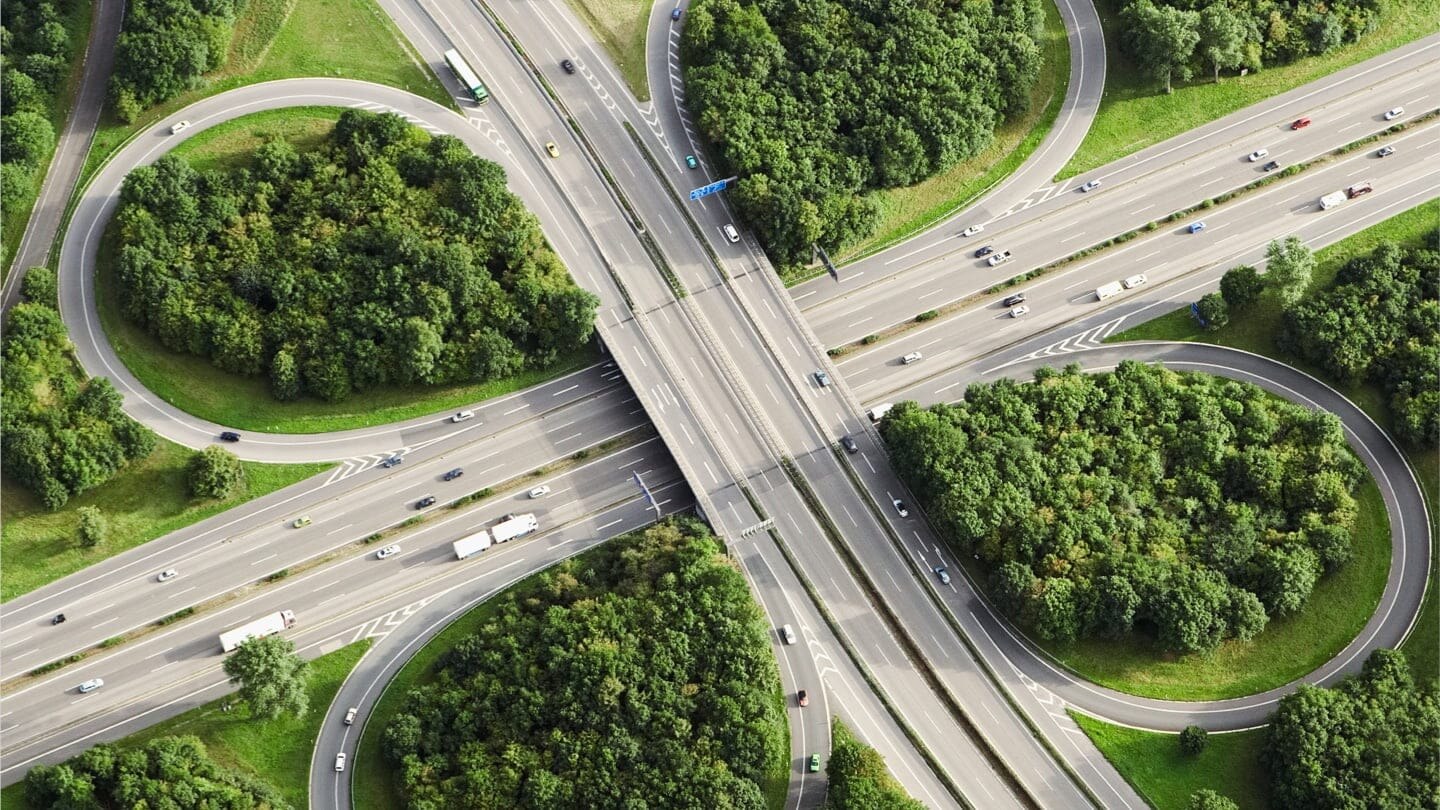 一张绿林环绕的高速公路交叉口的航拍照片.
