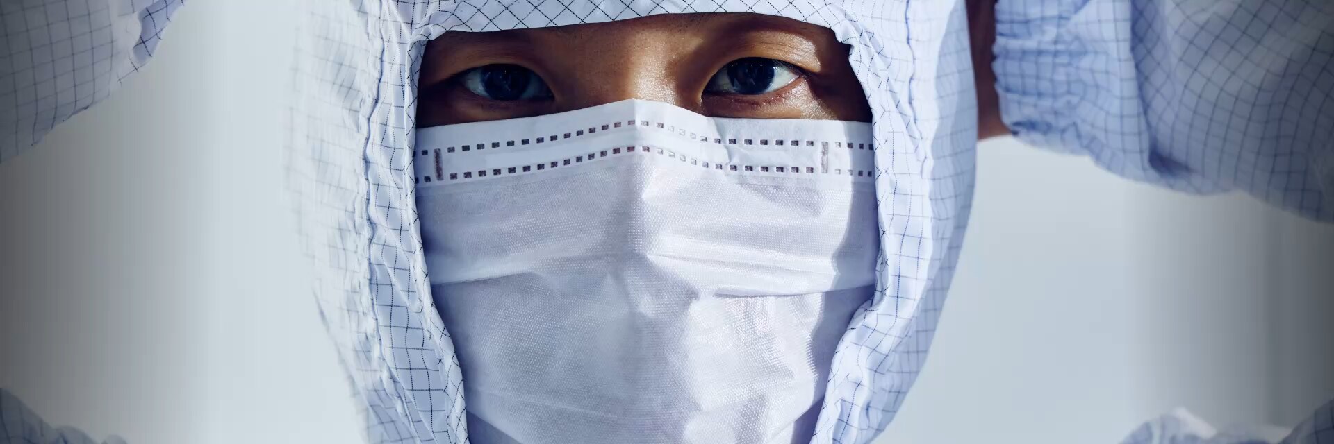 一位戴着防护头罩和口罩的洁净室技术人员的特写图片