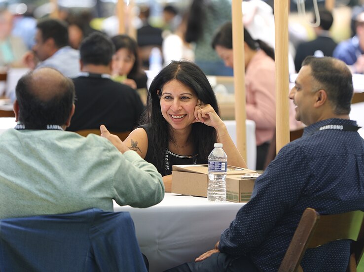 Attendees of the SAFE™ Forum 2025 enjoy a casual outdoor lunch under canopy tents, engaging in friendly conversation around a white-cloth