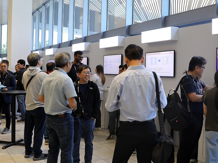 Attendees explore interactive digital displays at the SAFE™ Forum 2025, engaging in discussions along a well-lit hallway with large windows.