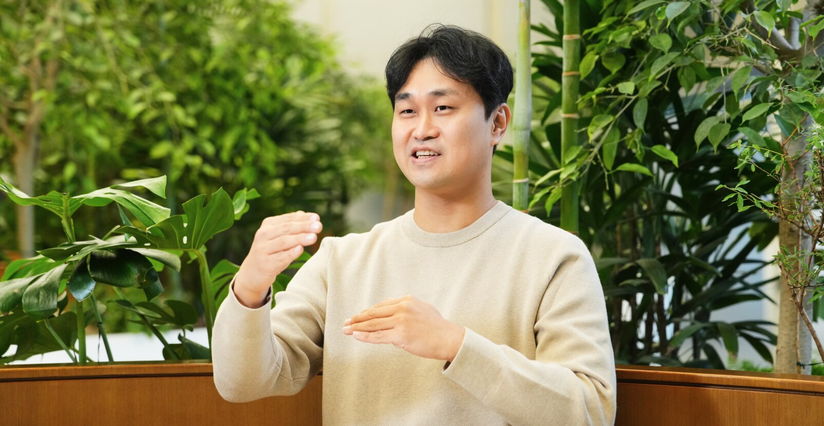 传感器解决方案团队的一名成员坐在充满植物的室内工作空间中，在面试时用手势说话。