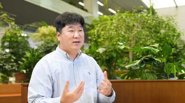 来自安全与电力产品开发团队的Lee，在室内绿植环境中以富有表情的手势和友好的语气发言