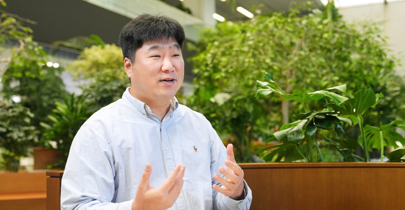 来自安全与电力产品开发团队的Lee，在室内绿植环境中以富有表情的手势和友好的语气发言