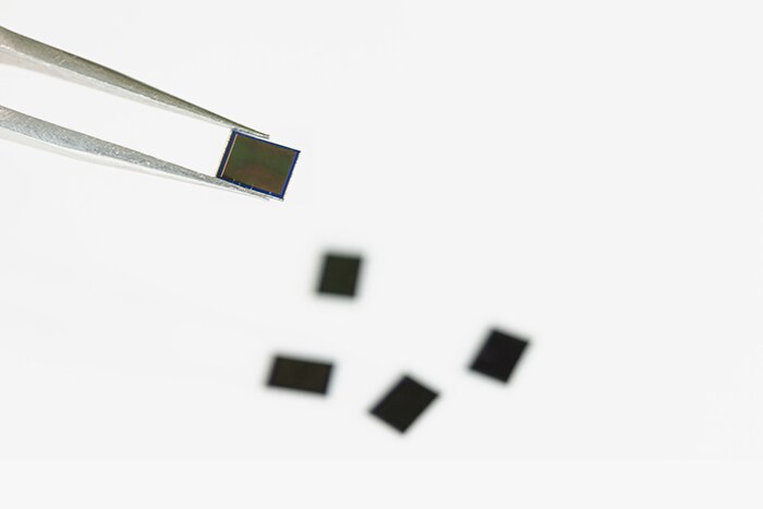 Holding the ISOCELL JN1 chip with tweezers.