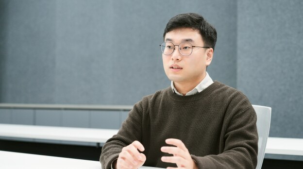 An engineer from the Memory Product Planning Team is speaking and gesturing during a meeting.