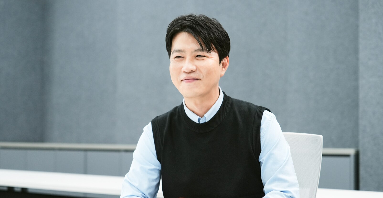A project leader from the Memory Product Planning Team is smiling while seated in a modern office with a soft gray background.