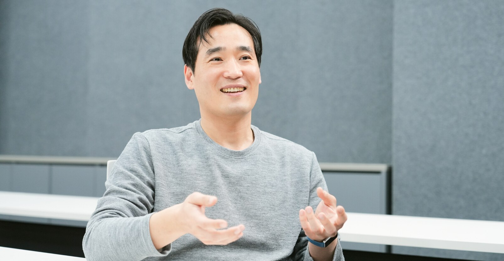 An engineer from the Technology Quality & Reliability Team is smiling as he explains with open hands.