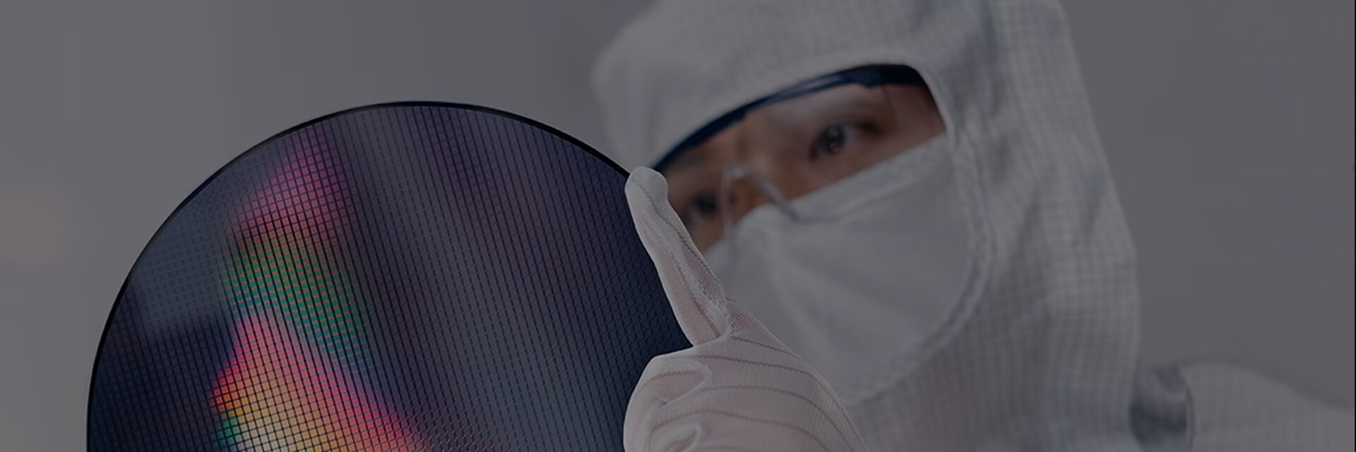 身穿无尘服和手套的工程师在洁净室环境中检查半导体晶圆表面