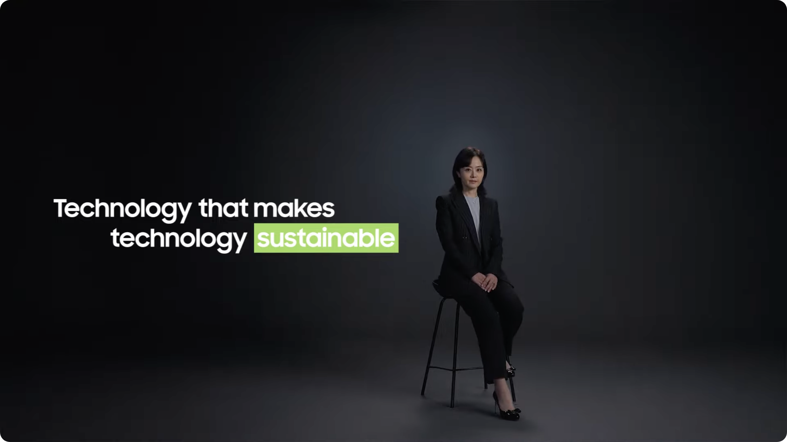 一位身穿黑色西装的女士坐在黑暗工作室的椅子上，旁边写着“让技术可持续发展的技术”