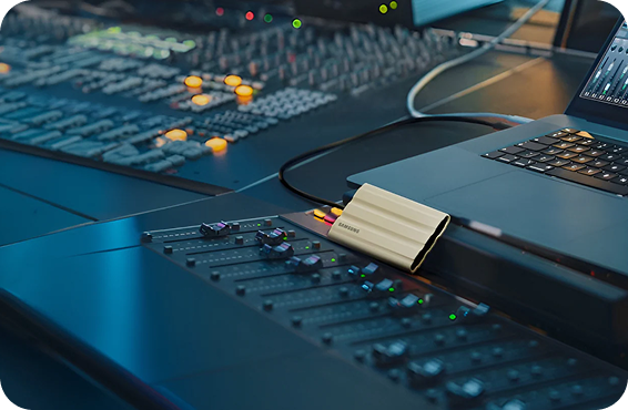 在录音棚环境中，一台三星外置固态硬盘与音频设备和笔记本电脑连接在一起。