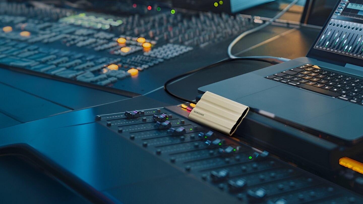 图中所示的 T7 Shield SSD 由回收铝制成，已连接到笔记本电脑和调音台。