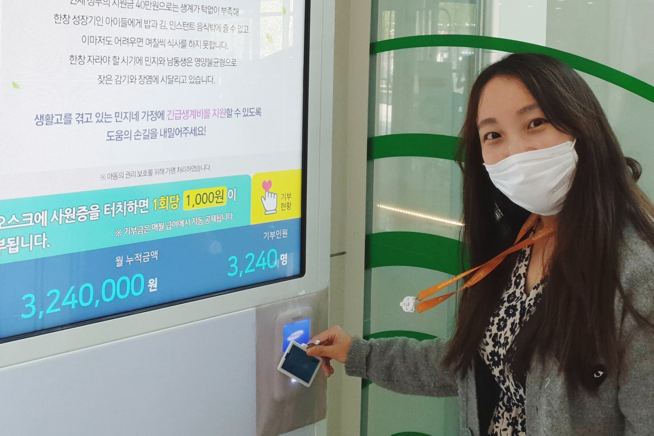 图为,戴着口罩的女职员在捐赠自助服务机拍摄职员证,看着前方。