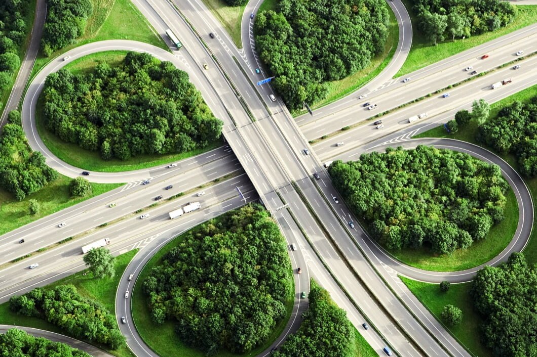 四叶式交汇处的天空俯视图，交汇处与高速公路之间有树木。